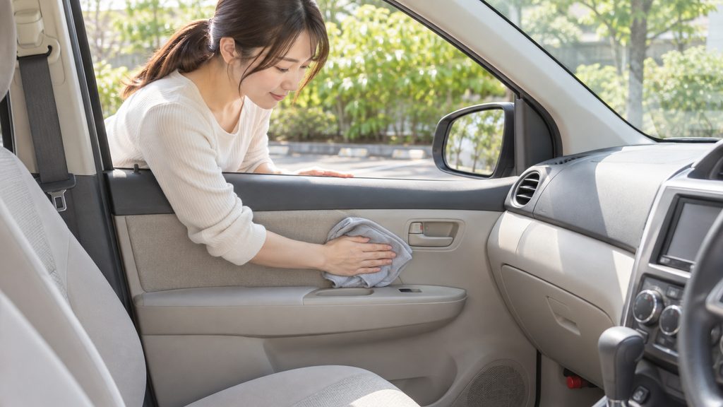 窓を開けて車内を拭き掃除する女性