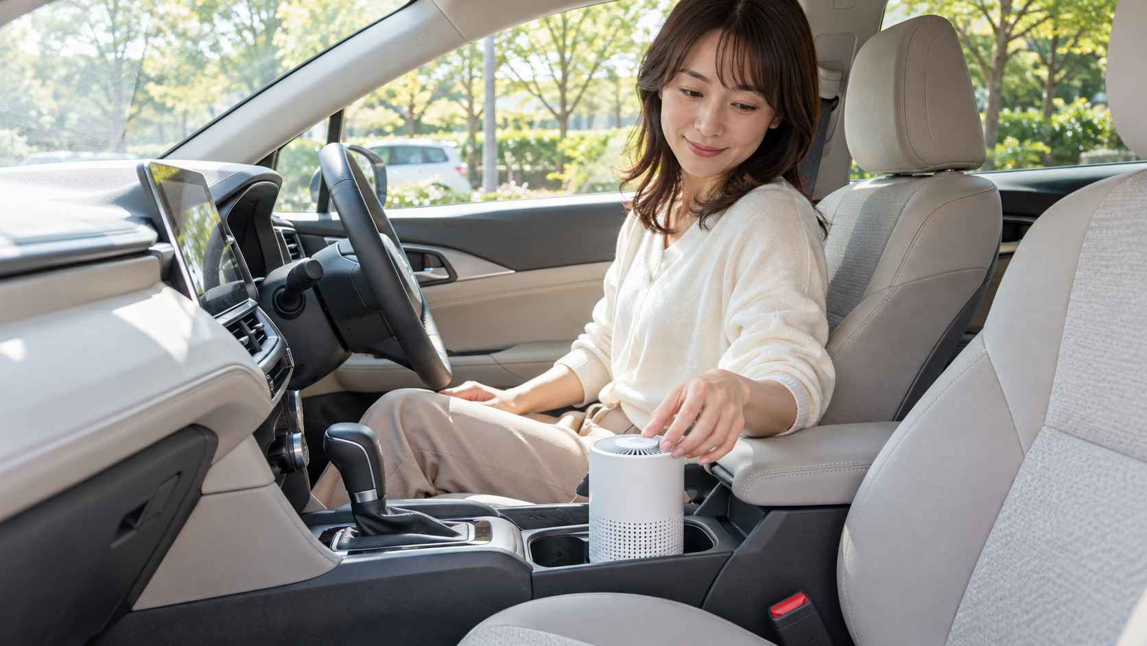 車内の小型空気清浄機を確認する女性